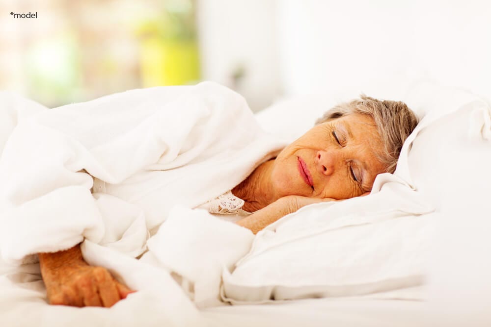 Older woman sleeping in bed.