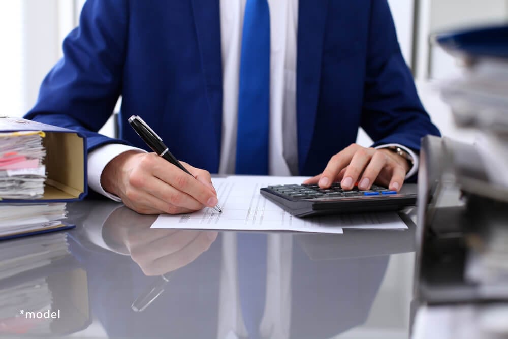 Man working over calculator and finance forms.