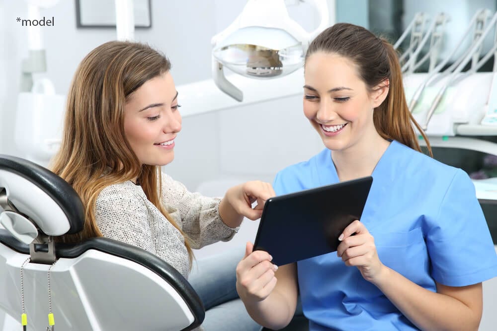 Girl in dentist chair, smiling with nurse.