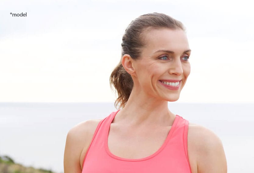 Older athletic woman smiling and looking off.