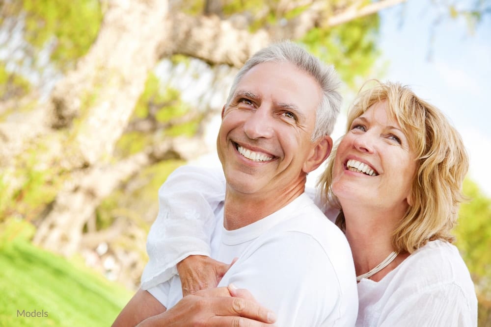 Middle aged couple smiling to show off their healthy teeth.