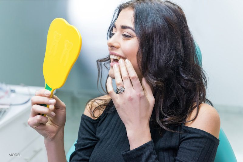  Lady checking teeth in mirror.