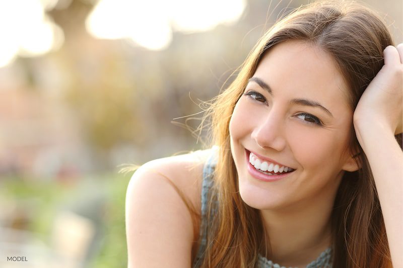 Woman with white teeth smiling outdoors