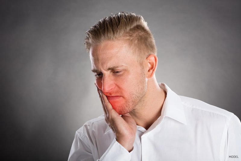 man dealing with jaw pain due to a tooth emergency.