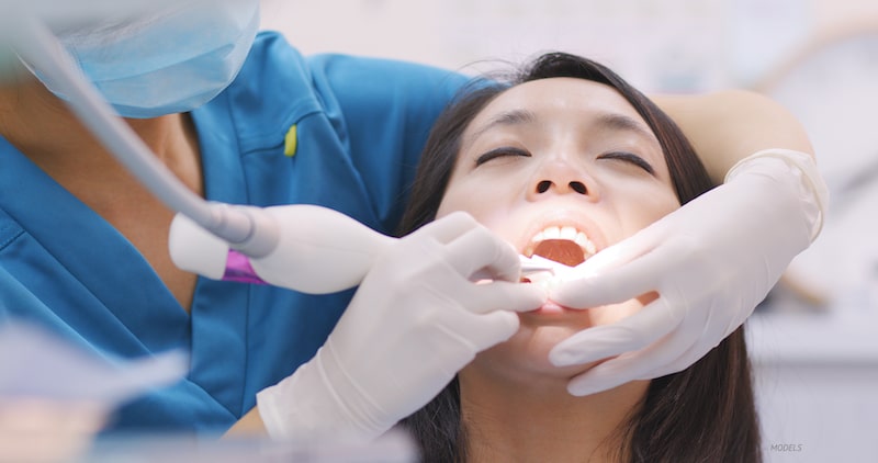 Woman getting a dental cleaning at dentist office