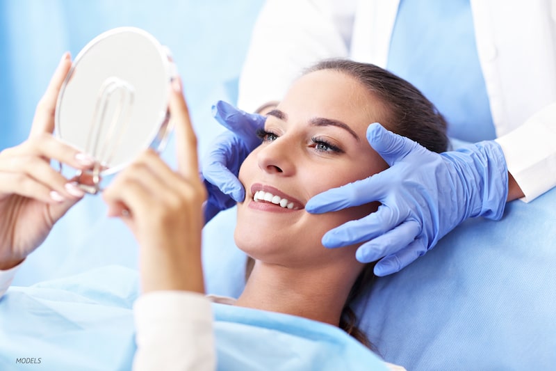 Woman looking into a mirror at a dentist's office.